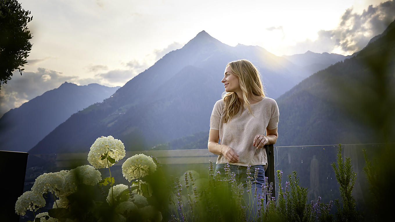 Eine Frau steht im Garten und genießt den Panoramablick im Hotel Das Sonnenparadies