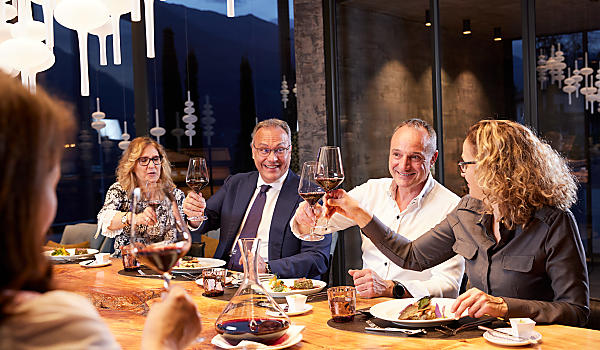 Mehrere Personen sitzen beim Tisch und amüsieren sich bei Getränken und Essen