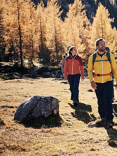 Zwei Menschen wandern durch Herbstlandschaft in Südtirol