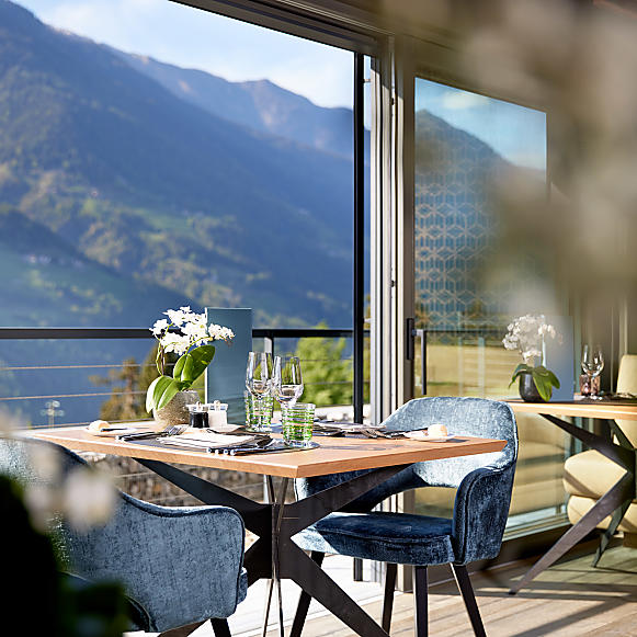 Panoramablick aus dem Restaurant im Hotel Das Sonnenparadies Blick auf einen gedeckten Tisch mit dem Panorama auf die Berge im Hintergrund