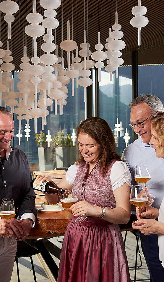Die Gastgeberin schenkt den Gästen ein Glas Bier ein 